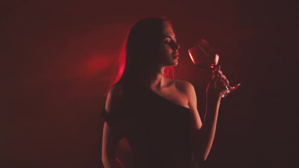 Γυναίκα με ένα ποτήρι κόκκινο κρασί σε κόκκινο καπνό — Αρχείο Βίντεο