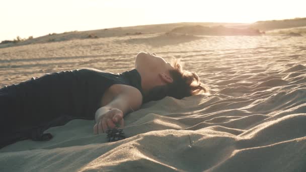 Mujer acostada en la arena al atardecer — Vídeos de Stock