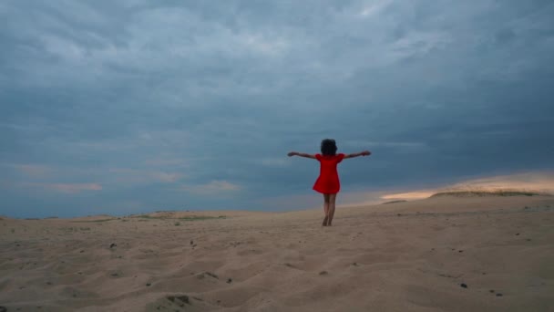 Kvinne i rød kjole som går i ørkenen – stockvideo
