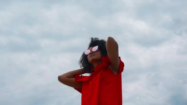 Porträt einer schönen afrikanisch-amerikanischen Frau in rotem Kleid auf Himmelshintergrund — Stockvideo