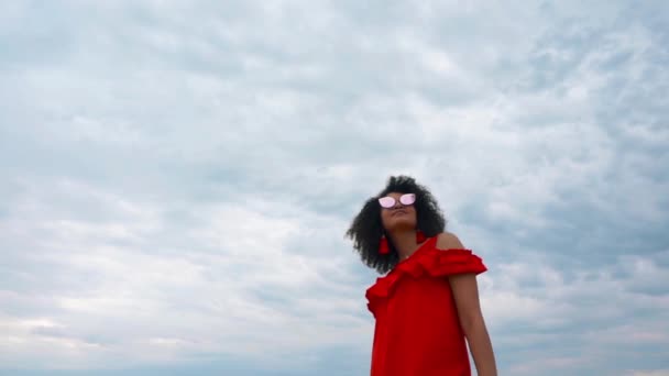 Ritratto di una bella donna afro-americana in abito rosso su sfondo cielo — Video Stock
