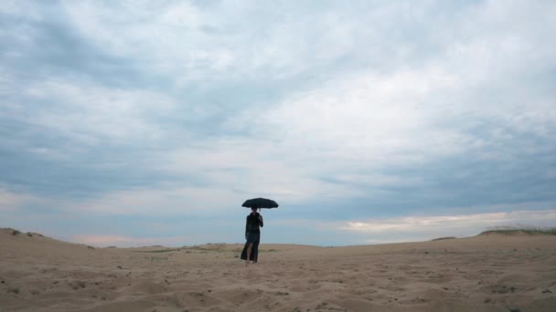Mujer caminando en el desierto con paraguas — Vídeos de Stock