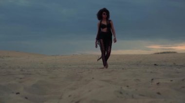 Sahilde yürüyen siyah elbiseli kadın