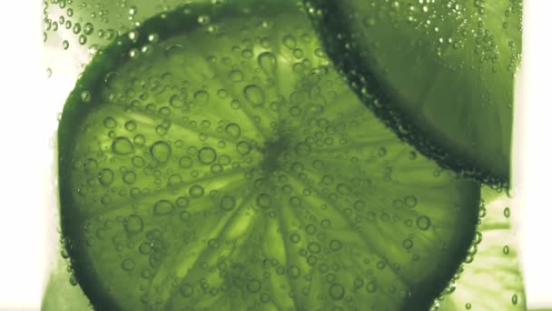 Sparkling bubbles water with a slice of lime — Stock Video