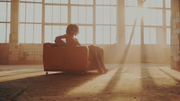 Woman sits in a red chair in the rays of light — Stock Video