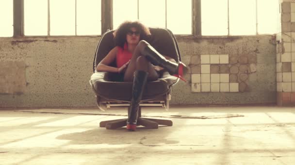 Sexy vrouw zit in een stoel in de stralen van het licht — Stockvideo