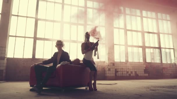 Женщина в противогазе с красной бутылкой дыма и мужчина в кресле — стоковое видео