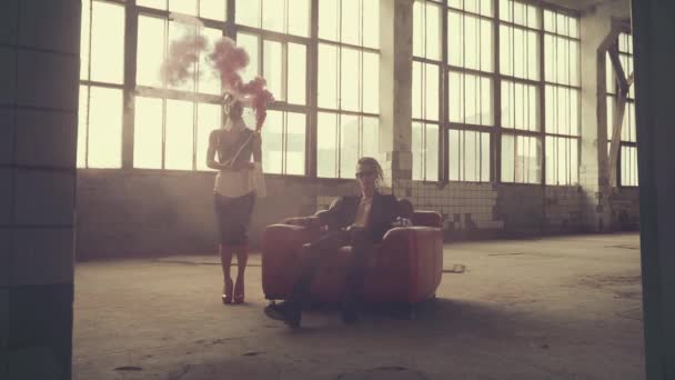 Woman in gas mask with a red bottle of smoke and man in an armchair — Stock Video