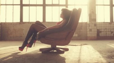 Seksi kadın ışık ışınları bir sandalyede oturur