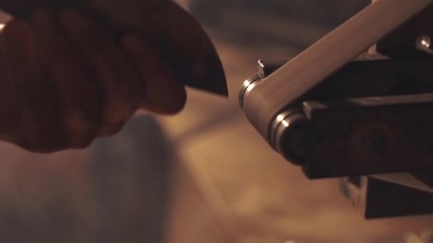 Homem afiando faca com faíscas. Trabalho em uma máquina de afiar . — Vídeo de Stock