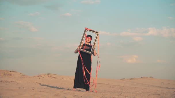 Mujer con los ojos vendados con marco de imagen en el desierto — Vídeos de Stock