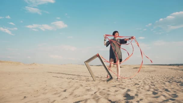 Mode. Vrouw geblinddoekt met fotolijstje in de woestijn — Stockvideo