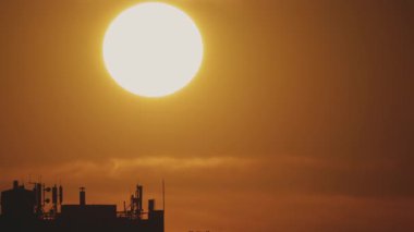 Büyük güneş ve şehrin çatılarının manzarası var. Zaman Uygulaması