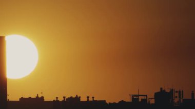 Büyük güneş ve şehrin çatılarının manzarası var. Zaman Uygulaması