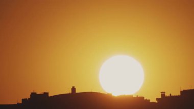 Büyük güneş ve şehrin çatılarının manzarası var. Zaman Uygulaması