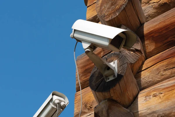 Primo piano di due videocamere imbullonate alla casa di tronchi e angolo del vecchio edificio in legno — Foto Stock