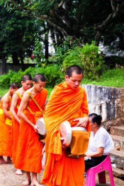 LUANG PRABANG, LAOS - SEPTEMBER15; Tanımlanamayan keşişler 15 Eylül 2012 'de bağış ve bağış toplamak için yürürler. Bu tören her gün sabah erkenden Luang Prabang 'da düzenlenir.
