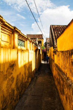 Hoi An, Vietnam 'daki binaların arasından geçen insanlar.