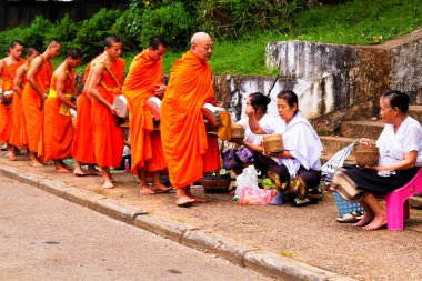 LUANG PRABANG, LAOS - SEPTEMBER15; Tanımlanamayan keşişler 15 Eylül 2012 'de bağış ve bağış toplamak için yürürler. Bu tören her gün sabah erkenden Luang Prabang 'da düzenlenir.