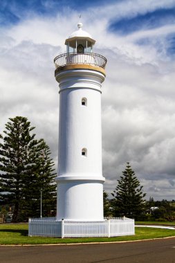 Deniz feneri sembolik olarak mavi gökyüzünün altındaki yeşil çimlerin üzerinde duruyor. Kiama, Yeni Güney Galler, Avustralya.