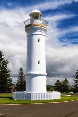 Deniz feneri sembolik olarak mavi gökyüzünün altındaki yeşil çimlerin üzerinde duruyor. Kiama, Yeni Güney Galler, Avustralya.