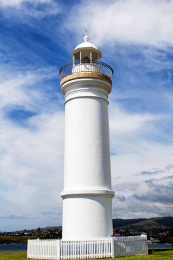Deniz feneri sembolik olarak mavi gökyüzünün altındaki yeşil çimlerin üzerinde duruyor. Kiama, Yeni Güney Galler, Avustralya.