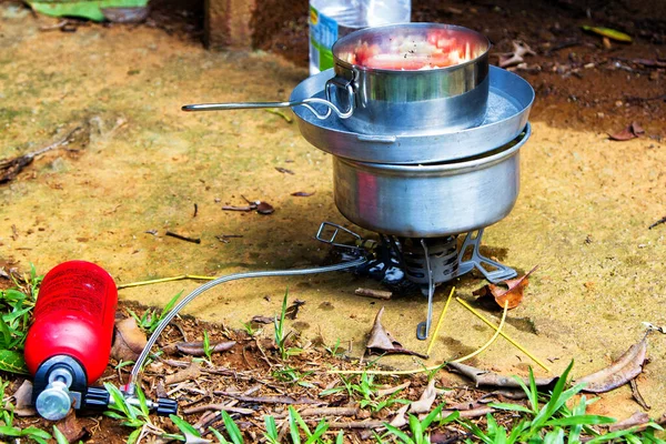 Preparing dinner on a fuel stove at a campsite.