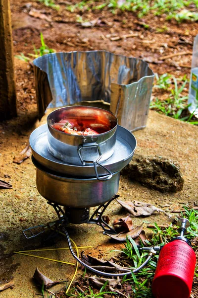 Preparing dinner on a fuel stove at a campsite.