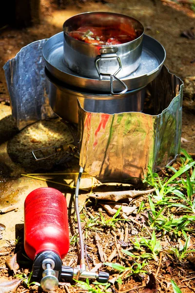 Preparing dinner on a fuel stove at a campsite.