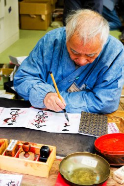 NARA, JAPONYA - 15 Ocak 2013 'te Japonya' nın Nara kentinde kimliği belirsiz bir adam bir kağıda Japon sembolleri ve bir fırça ve mürekkep kullanarak Japonca semboller yazdı. Kaligrafi Japonya 'da kullanılan popüler bir yazı sanatıdır..