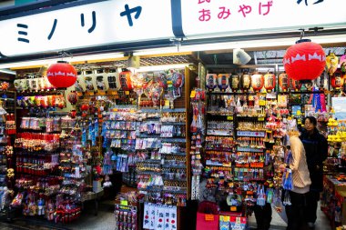 TOKYO, JAPONYA - 15 Ocak 2013 'te Japonya, Tokyo' da bir hatıra seçmek için personel müşteriye yardımcı olur. Asakusa 'da çok sayıda hediyelik eşya tezgahı var çünkü popüler bir turizm beldesi..