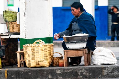 OTAVALO, ECUADOR - NOV 6, 2019: Geleneksel giysiler içinde tanımlanamayan Ekvadorlu kadın Otavalo Market 'te çalışıyor. Ekvador halkının% 71,9 'u Mestizo etnik grubuna ait.