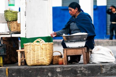 OTAVALO, ECUADOR - NOV 6, 2019: Geleneksel giysiler içinde tanımlanamayan Ekvadorlu kadın Otavalo Market 'te çalışıyor. Ekvador halkının% 71,9 'u Mestizo etnik grubuna ait.