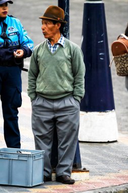 OTAVALO, ECUADOR - NOV 6, 2019: Geleneksel kıyafetler içindeki tanımlanamayan Ekvadorlu adam Otavalo Market 'te çalışıyor. Ekvador halkının% 71,9 'u Mestizo etnik grubuna ait.