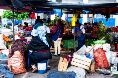 OTAVALO, ECUADOR - NOV 6, 2019: Geleneksel giysiler içinde tanımlanamayan Ekvadorlu kadın Otavalo Market 'te çalışıyor. Ekvador halkının% 71,9 'u Mestizo etnik grubuna ait.