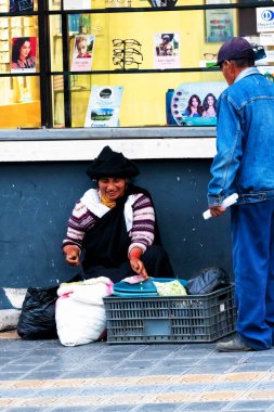 OTAVALO, ECUADOR - NOV 6, 2019: Geleneksel giysiler içinde tanımlanamayan Ekvadorlu kadın Otavalo Market 'te çalışıyor. Ekvador halkının% 71,9 'u Mestizo etnik grubuna ait.