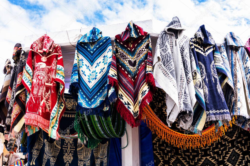Traditional ponchos in different colors on display in Otavalo artisan Market in Ecuador.