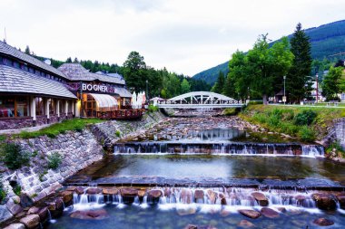 SpINDLERUV MLYN, CZECH REPUBLIC - 13 AUG 2019: Elbe (Lave) nehri Spindleruv Mlyn şehir merkezi boyunca akar - popüler turist yürüyüşü ve kış kayak merkezi. Krkonose Dağları
