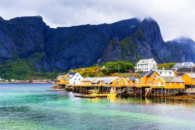 Norveç 'in Lofoten Adaları' ndaki kırmızı ve sarı rorbu evleriyle ünlü bir turistik bölge olan Hamnoy balıkçı köyü. Sakin, bulanık su