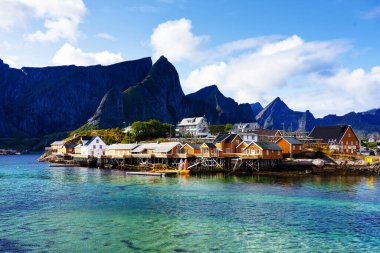 Norveç 'in Lofoten Adaları' ndaki kırmızı ve sarı rorbu evleriyle ünlü bir turistik bölge olan Hamnoy balıkçı köyü. Sakin, bulanık su