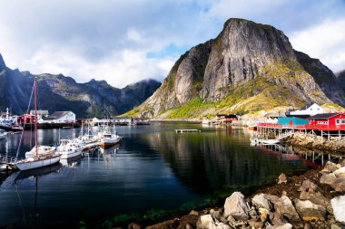 Norveç 'in Lofoten Adaları' ndaki kırmızı ve sarı rorbu evleriyle ünlü bir turistik bölge olan Hamnoy balıkçı köyü. Sakin, bulanık su
