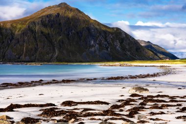 Kristal turkuaz suyla yıkanmış beyaz kumlar. Norveç, Lofoten Adaları 'ndaki Ramberg plajından deniz manzarası