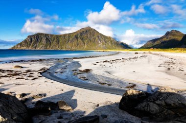 Kristal turkuaz suyla yıkanmış beyaz kumlar. Norveç, Lofoten Adaları 'ndaki Ramberg plajından deniz manzarası