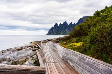 The boardwalk at Tungeneset leads to spectacular view of the iconic Devils Jaw on the arctic island of Senja in northern Norway. clipart