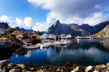Norveç 'in Lofoten Adaları' ndaki kırmızı ve sarı rorbu evleriyle ünlü bir turistik bölge olan Hamnoy balıkçı köyü. Sakin, bulanık su