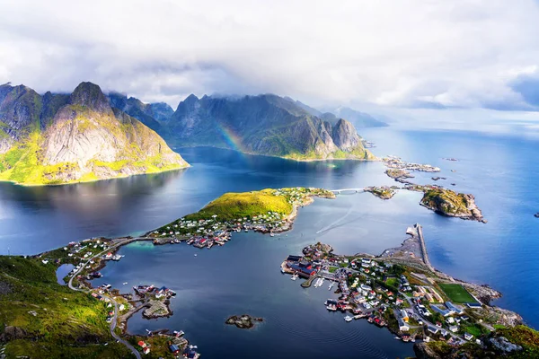 从Reinebringen山脊俯瞰挪威Lofoten岛上令人震惊的高山和Reine村的阳光鸟瞰全景 有彩虹和崎岖山峰的风景美景 — 图库照片