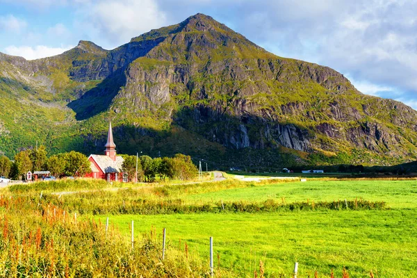 Flakstad Church with mountains in the background, exquisite XVIII century baroque masterpiece in the Arctic, Flakstadoy, Lofoten Islands, North of the Arctic Circle, Norway