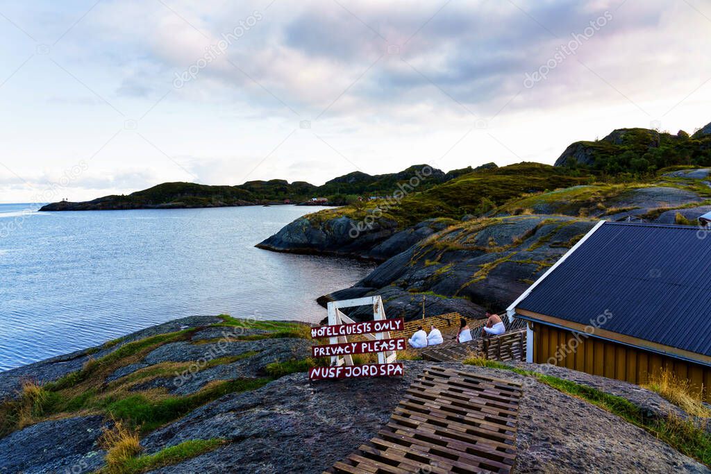NUSFJORD, NORWAY - SEPT 10, 2019: People relaxing and enjoying views in an outdoor spa in Nusfjord, Lofoten, Norway