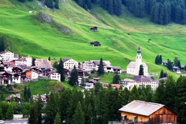 Dağların manzarası ve Grigioni kantonuna ait küçük bir köy. Arka planda resimli bir kilise var..