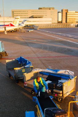 AMSTERDAM, NETHERLANDS - NOVEMBER 08: 08 Kasım 2014 tarihinde Hollanda 'nın Amsterdam Schiphol havaalanında bir uçaktan bavul indiren adam. Schiphol, Avrupa 'nın dördüncü büyük havaalanıdır..